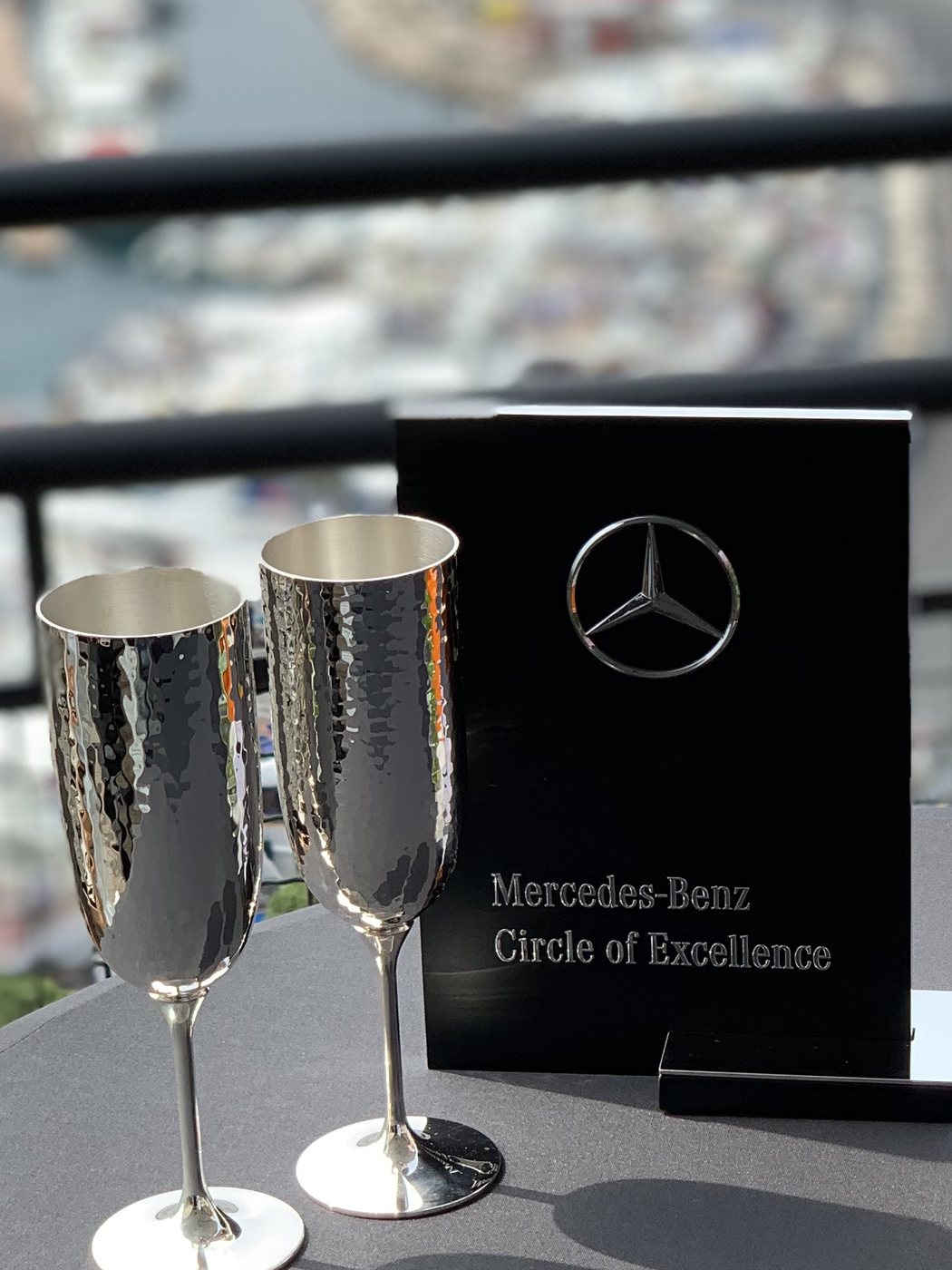 The Mercedes-Benz table card and silver flutes on the terrace, the circuit behind